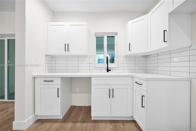 kitchen featuring backsplash, a sink, white cabinets, and light wood-style floors