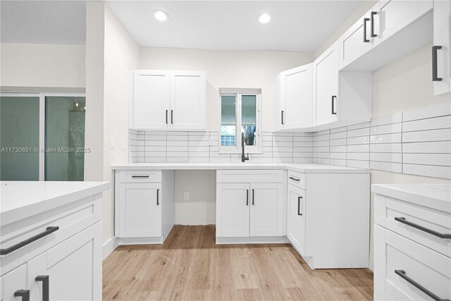 kitchen featuring sink, white cabinets, light wood-type flooring, and decorative backsplash