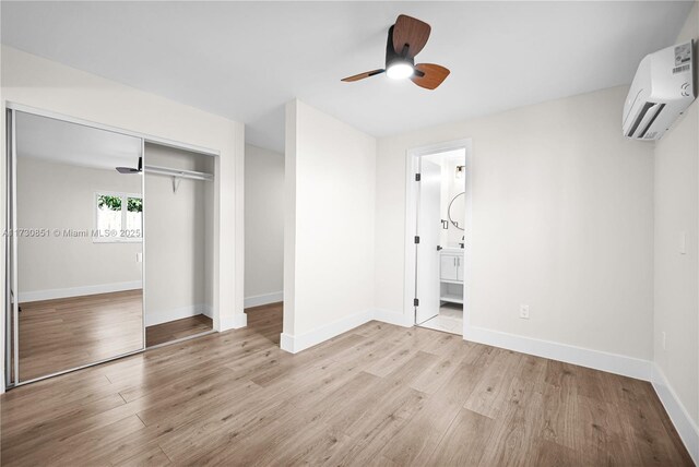 unfurnished room featuring a wall unit AC, ceiling fan, and light wood-type flooring