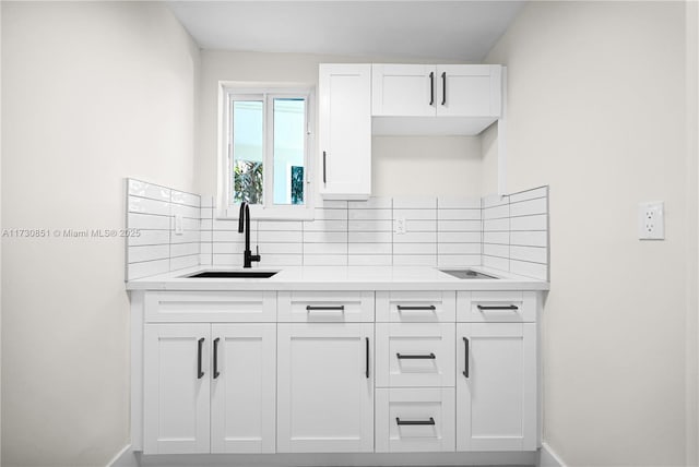 kitchen featuring white cabinetry, decorative backsplash, a sink, and light countertops