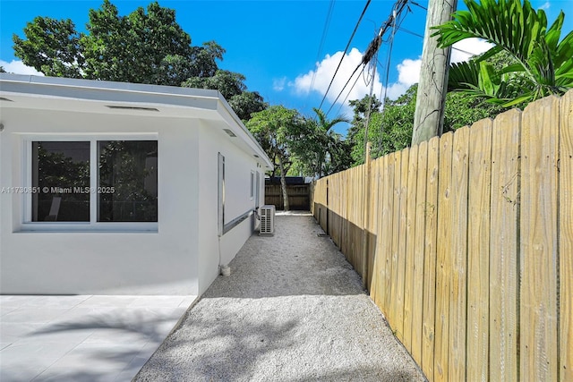 view of property exterior with fence, a patio, and stucco siding