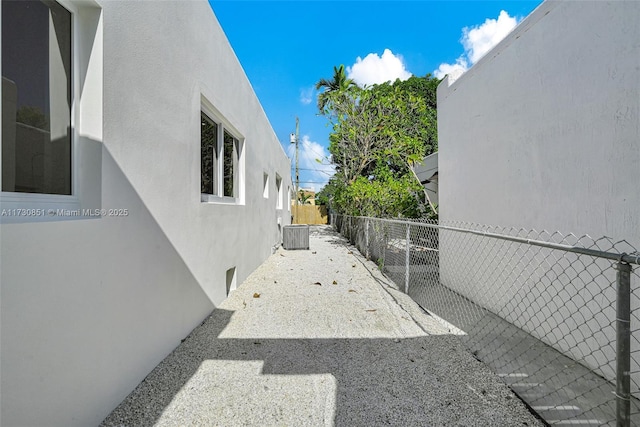 view of home's exterior with central AC unit, fence, and stucco siding