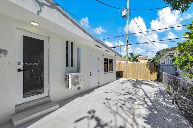 exterior space with entry steps, ac unit, fence, a patio area, and stucco siding