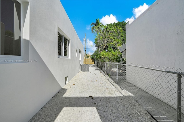 view of side of home featuring central air condition unit, fence, and stucco siding