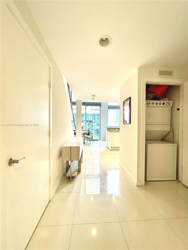 hall with tile patterned floors, stacked washer / dryer, and floor to ceiling windows