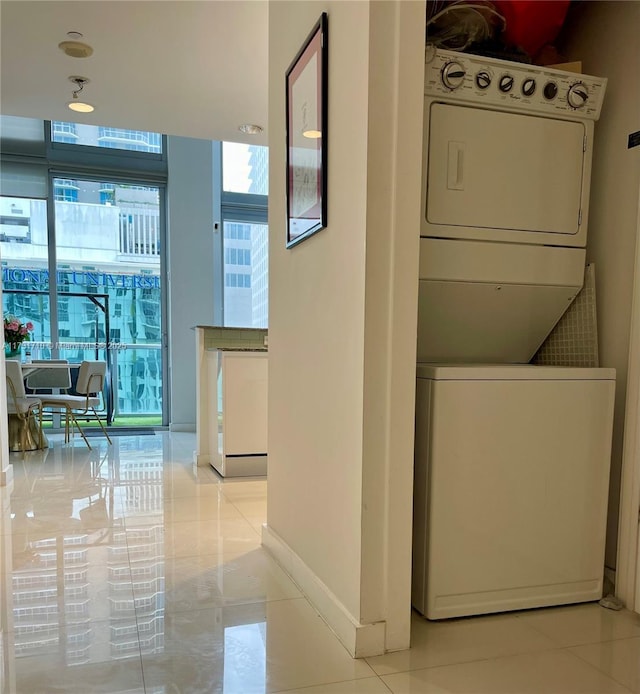 laundry room with light tile patterned flooring and stacked washer / dryer