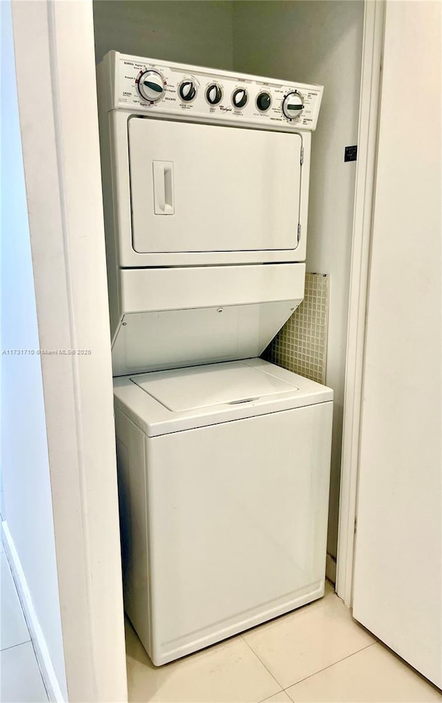 washroom with stacked washer / dryer and light tile patterned floors