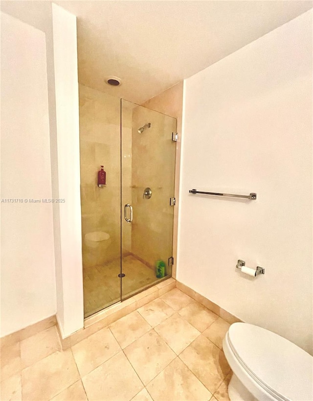 bathroom with tile patterned floors, a shower with door, and toilet