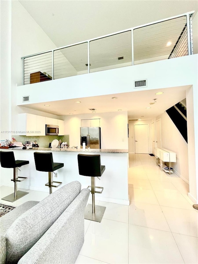 living room with light tile patterned flooring and a towering ceiling