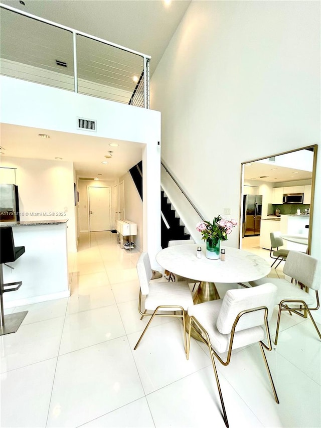 dining space featuring a high ceiling and light tile patterned floors