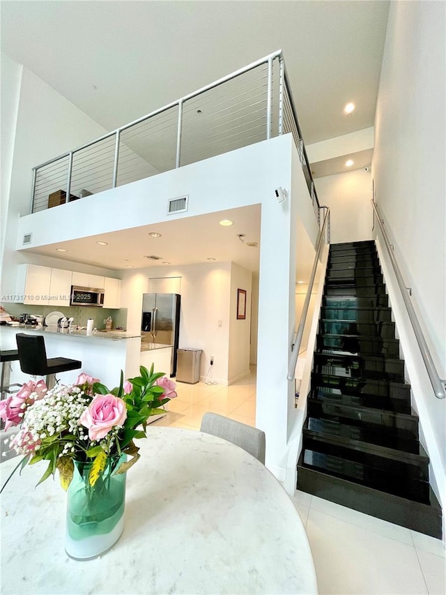 stairs with a towering ceiling and tile patterned floors