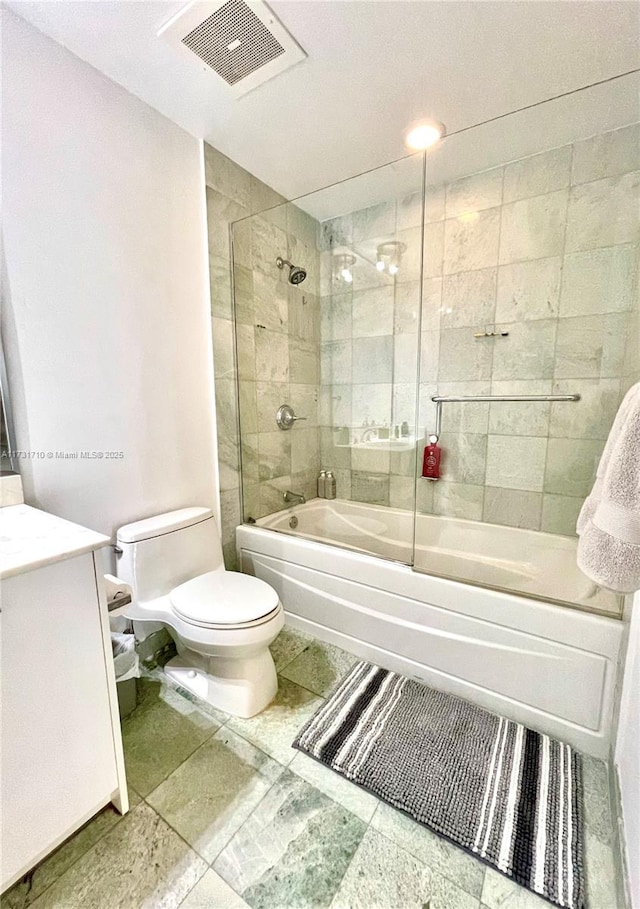 full bathroom with enclosed tub / shower combo, vanity, and toilet