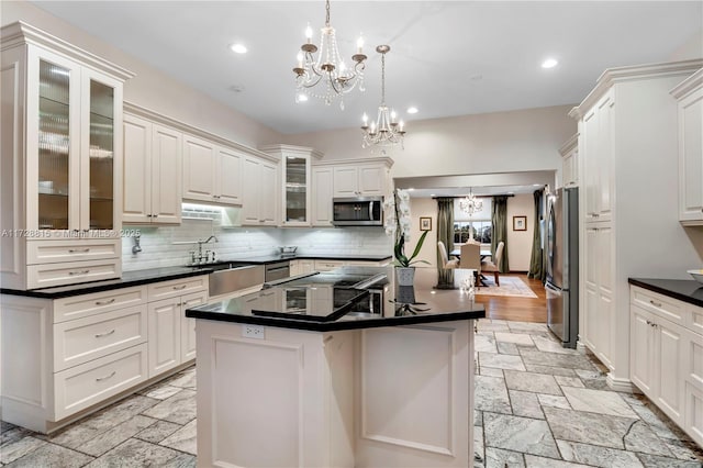 kitchen with a kitchen island, appliances with stainless steel finishes, white cabinets, hanging light fixtures, and a notable chandelier