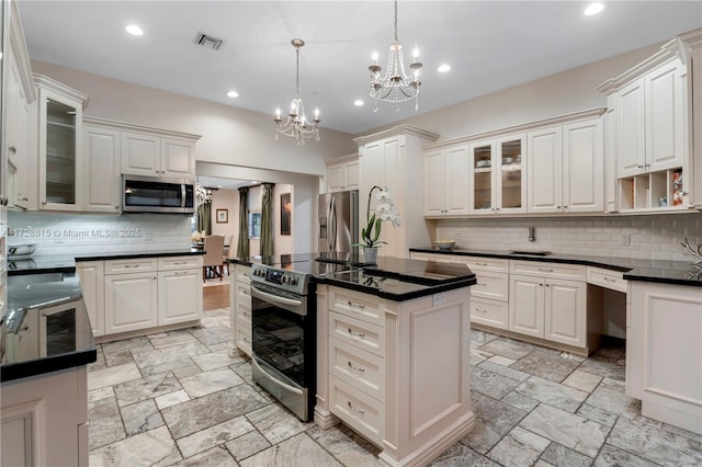 kitchen with tasteful backsplash, stainless steel appliances, hanging light fixtures, and white cabinets