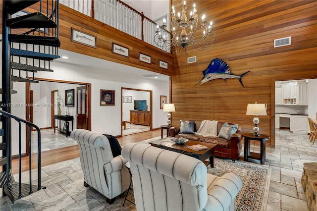 living room with a notable chandelier, wooden walls, and a high ceiling