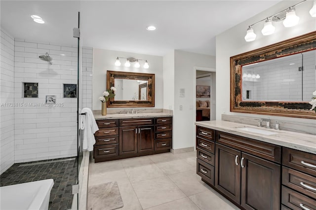 bathroom with tile patterned flooring, vanity, and tiled shower