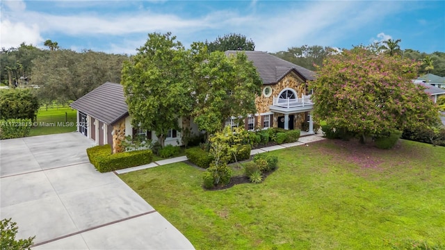 view of front of property featuring a balcony, a garage, and a front yard