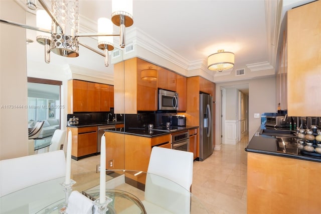 kitchen featuring crown molding, an inviting chandelier, tasteful backsplash, hanging light fixtures, and appliances with stainless steel finishes