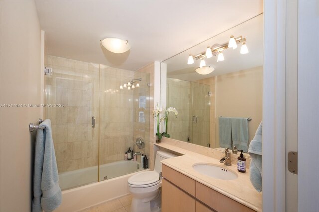 full bathroom with bath / shower combo with glass door, vanity, tile patterned floors, and toilet