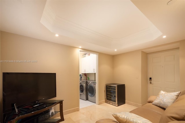 living room featuring a raised ceiling, washing machine and clothes dryer, and beverage cooler