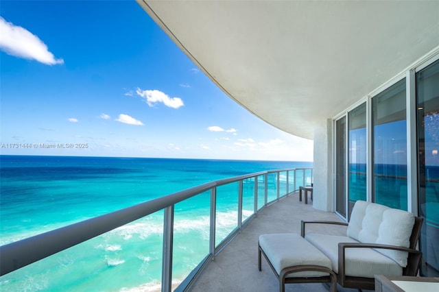 balcony with a water view and a view of the beach