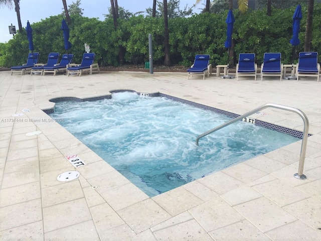 view of swimming pool featuring a hot tub and a patio