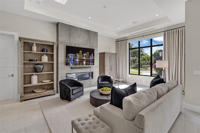 living room with a premium fireplace and a tray ceiling