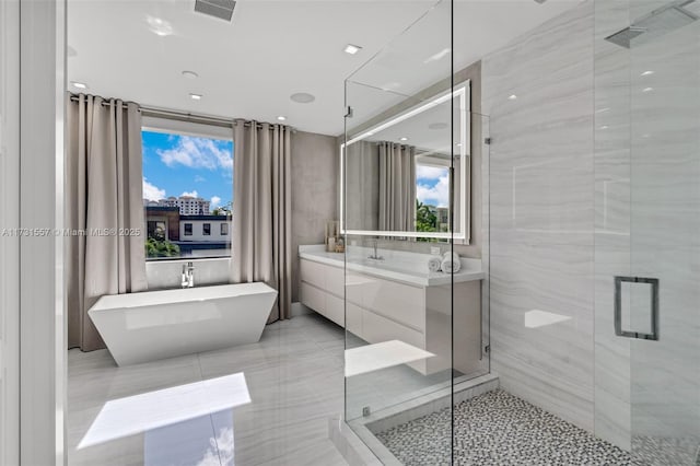 bathroom with shower with separate bathtub, a wealth of natural light, vanity, and tile walls