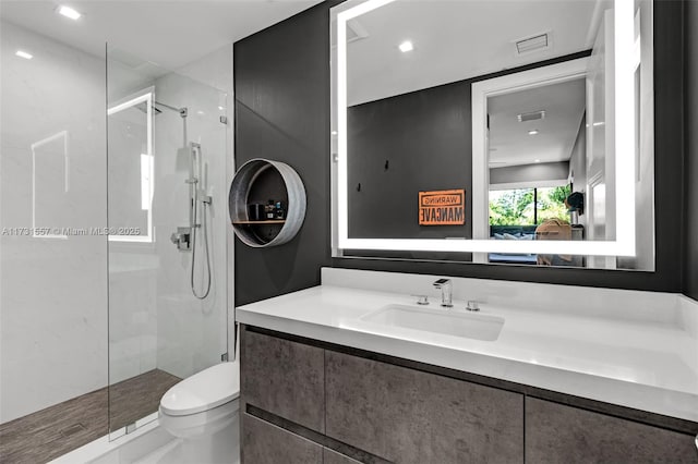 bathroom with vanity, toilet, and tiled shower