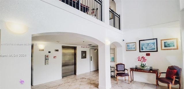 corridor with a towering ceiling and elevator