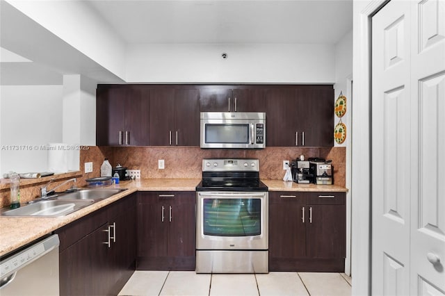 kitchen with light tile patterned floors, stainless steel appliances, light countertops, decorative backsplash, and a sink