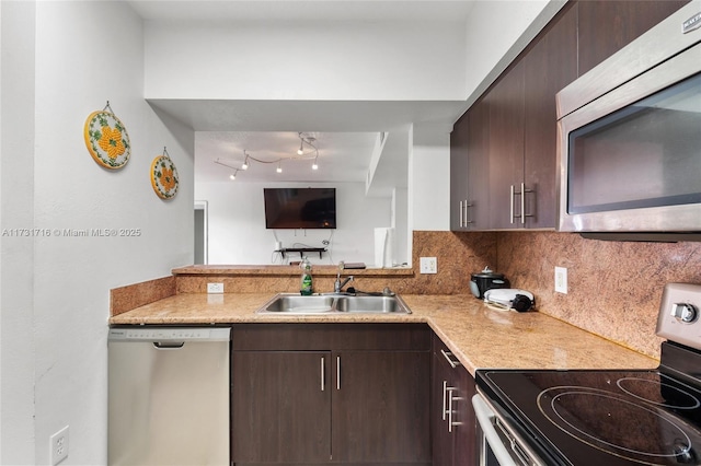 kitchen with a sink, dark brown cabinets, appliances with stainless steel finishes, tasteful backsplash, and modern cabinets