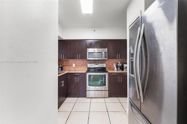 kitchen featuring light tile patterned floors, appliances with stainless steel finishes, light countertops, and backsplash