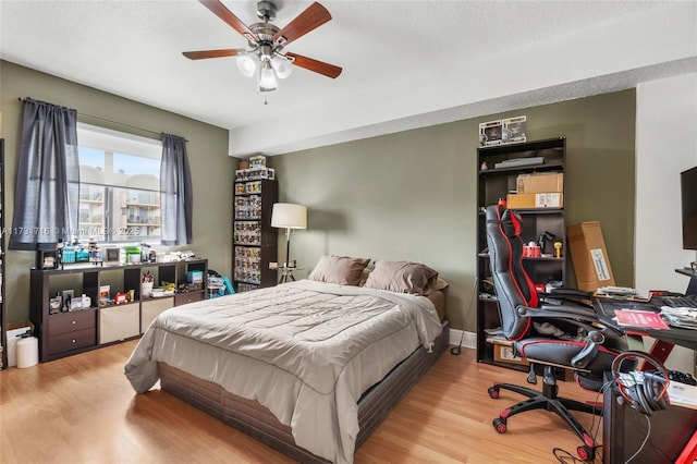 bedroom featuring a textured ceiling, light wood-type flooring, a ceiling fan, and baseboards