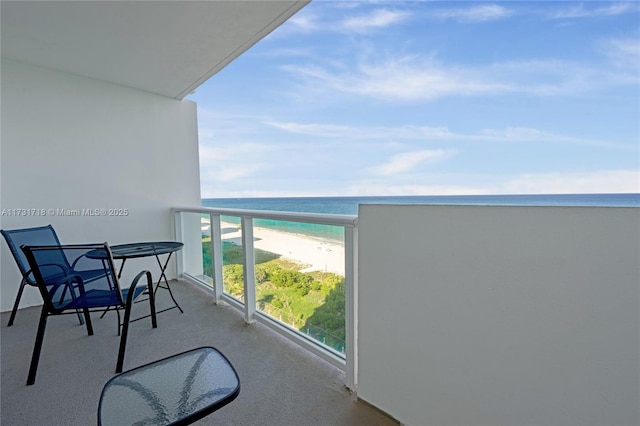 balcony with a water view and a view of the beach