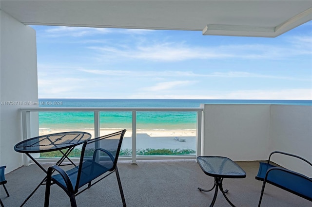 balcony featuring a view of the beach and a water view