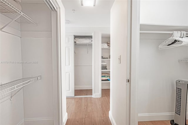 spacious closet with heating unit and hardwood / wood-style flooring