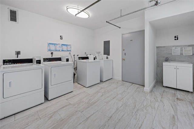 washroom with sink, tile walls, electric panel, and washer and clothes dryer