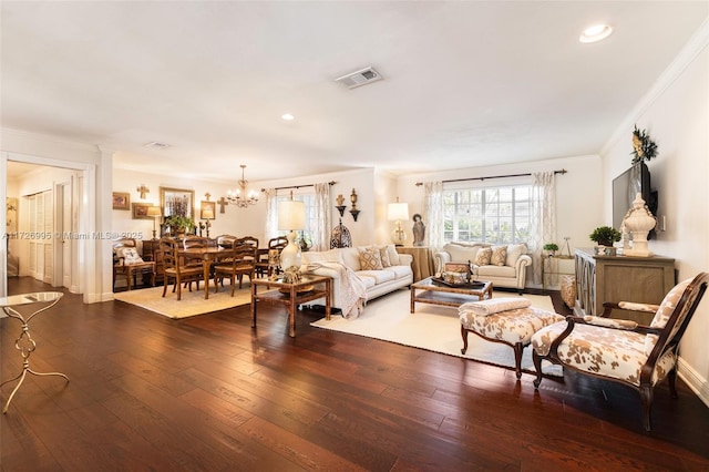 living room featuring dark wood-type flooring, ornamental molding, and a chandelier