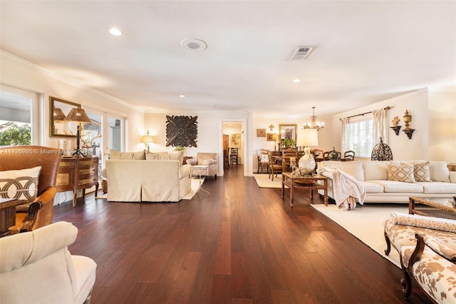 living room featuring dark hardwood / wood-style flooring, ornamental molding, and an inviting chandelier