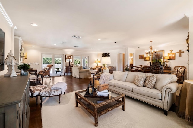 living room featuring hardwood / wood-style flooring, ornamental molding, and an inviting chandelier