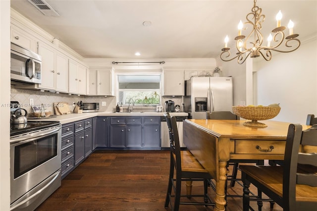 kitchen with pendant lighting, sink, white cabinets, and appliances with stainless steel finishes