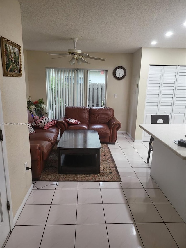 living room with ceiling fan, light tile patterned floors, and a textured ceiling