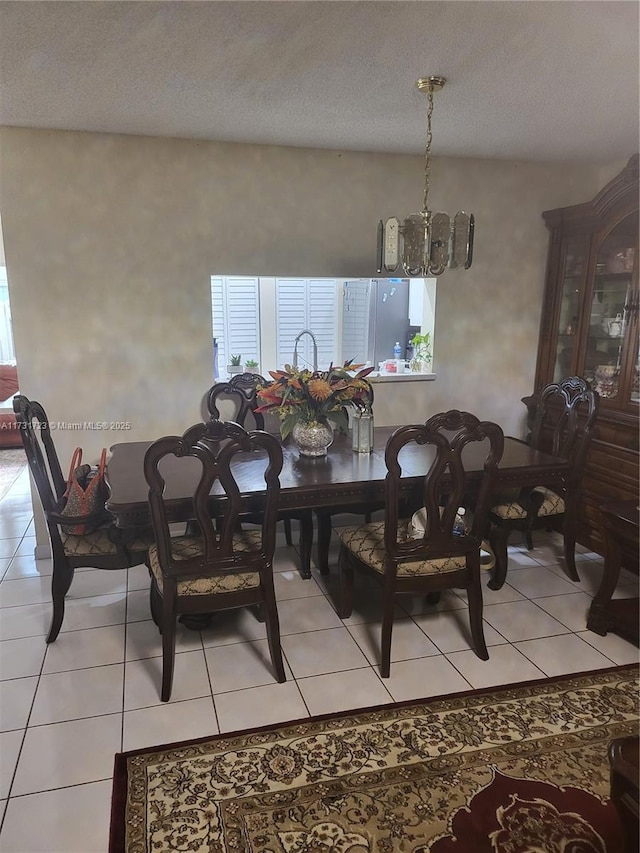 dining space featuring light tile patterned floors, a chandelier, and a textured ceiling