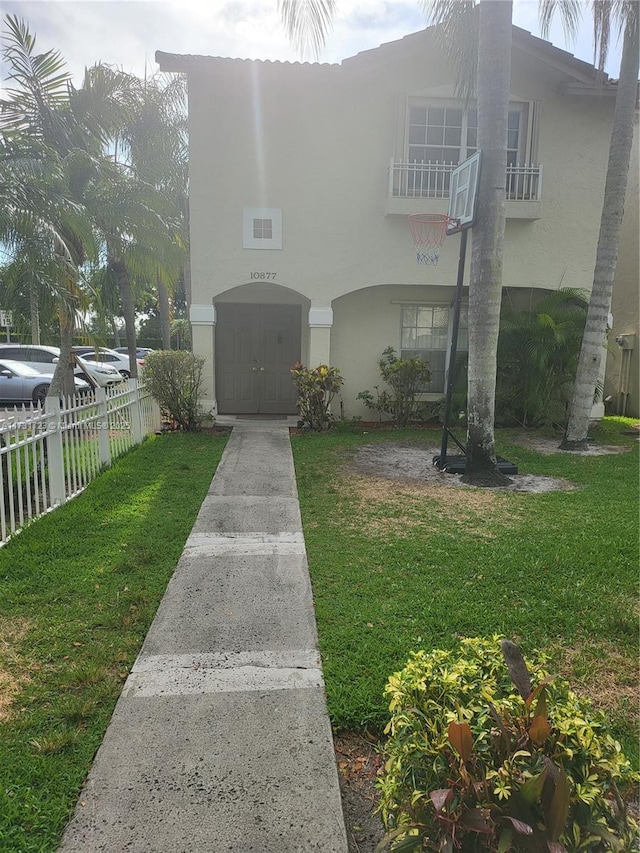 view of front of house with a front lawn and a balcony