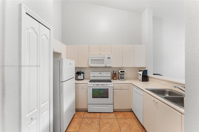 kitchen with light tile patterned floors, light countertops, a high ceiling, a sink, and white appliances