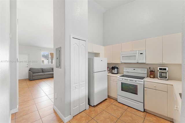 kitchen featuring light tile patterned floors, light countertops, a towering ceiling, open floor plan, and white appliances