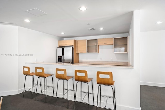 kitchen featuring a kitchen breakfast bar, stainless steel fridge, kitchen peninsula, and light brown cabinetry