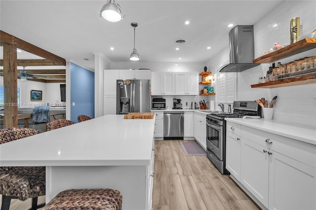 kitchen with wall chimney exhaust hood, appliances with stainless steel finishes, and white cabinets