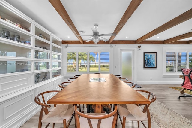 dining space with light hardwood / wood-style flooring, beamed ceiling, and plenty of natural light